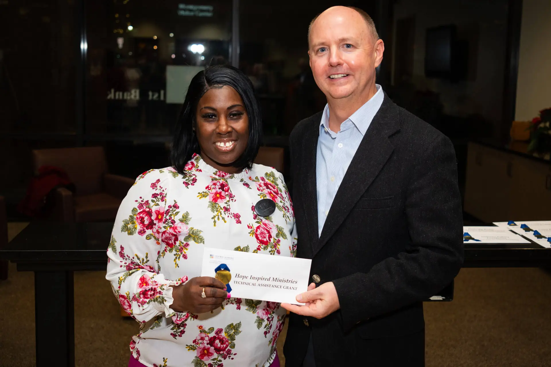 Man from CACF awarding technical assistance grant money to a woman from Hope Inspired Ministries