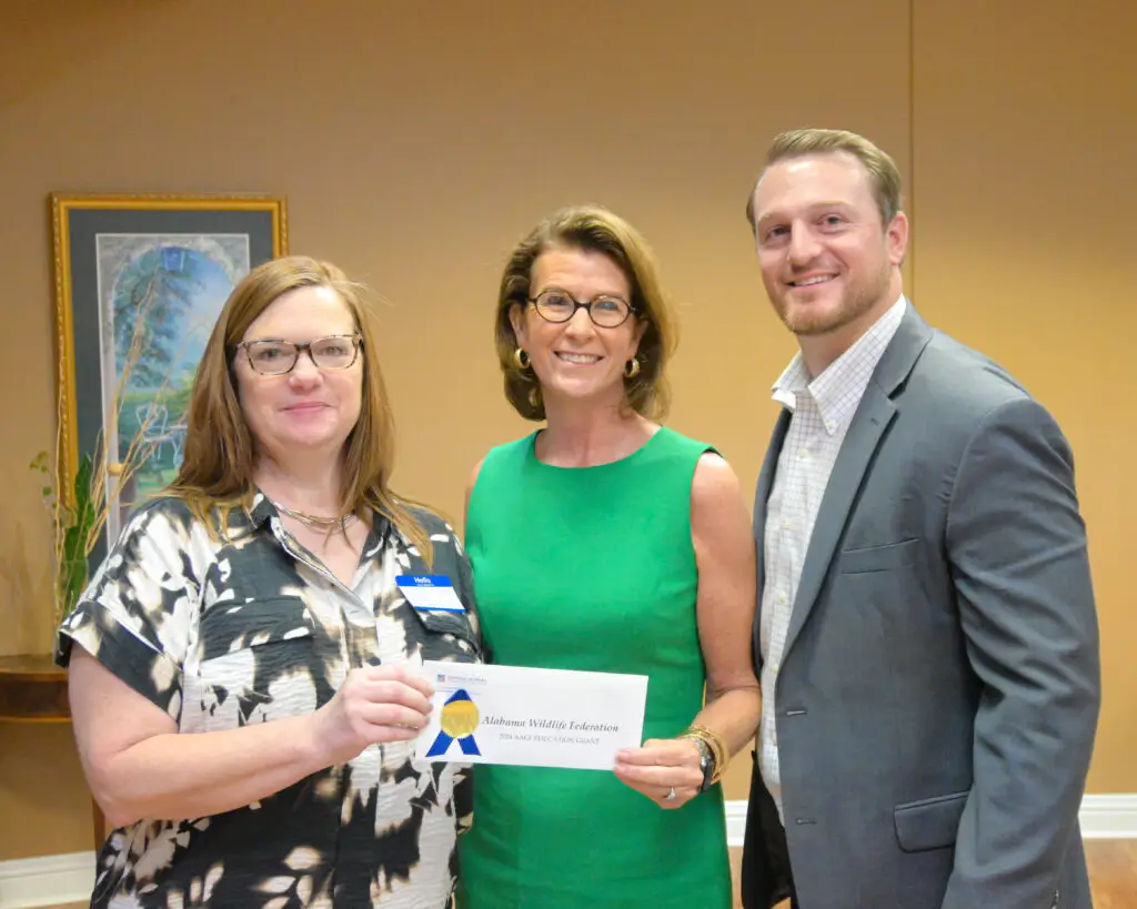 Burton Crenshaw in green smiling with two recipients of education grants from CACF