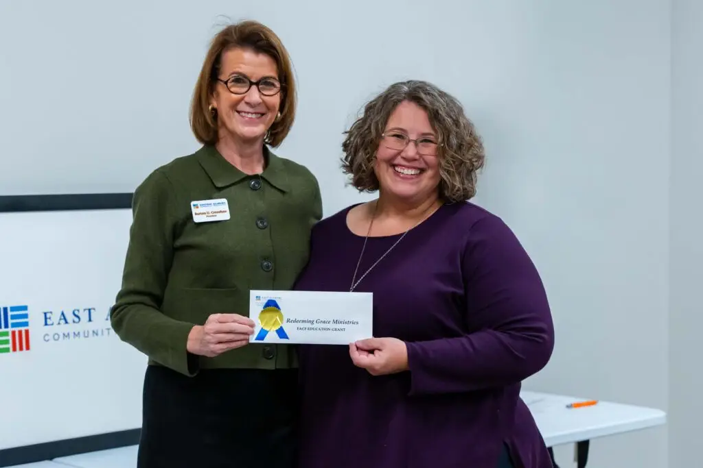 Burton Crenshaw posing with grant recipient holding envelope and smiling