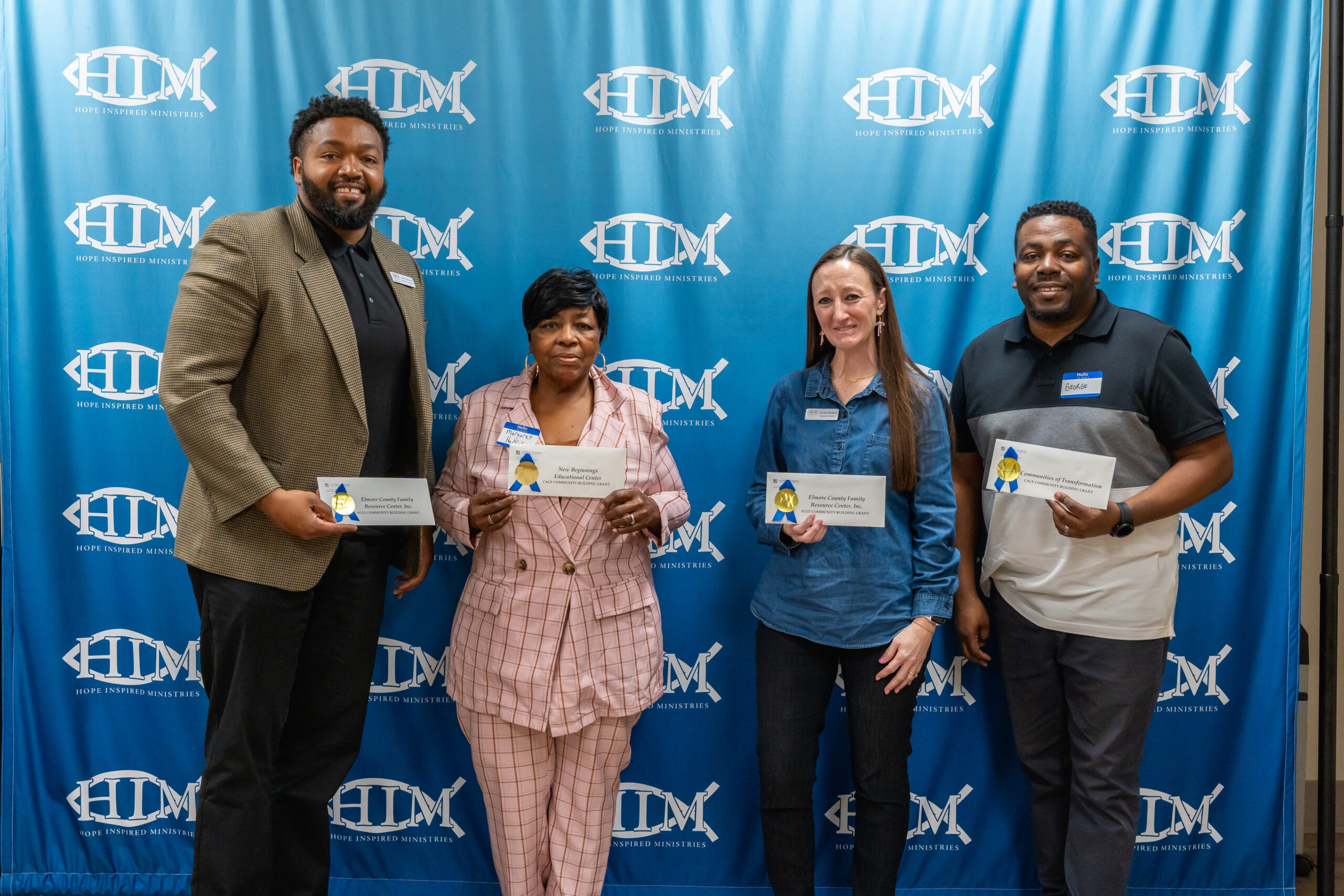 group of 4 non profit representatives holding their grant award envelopes from CACF