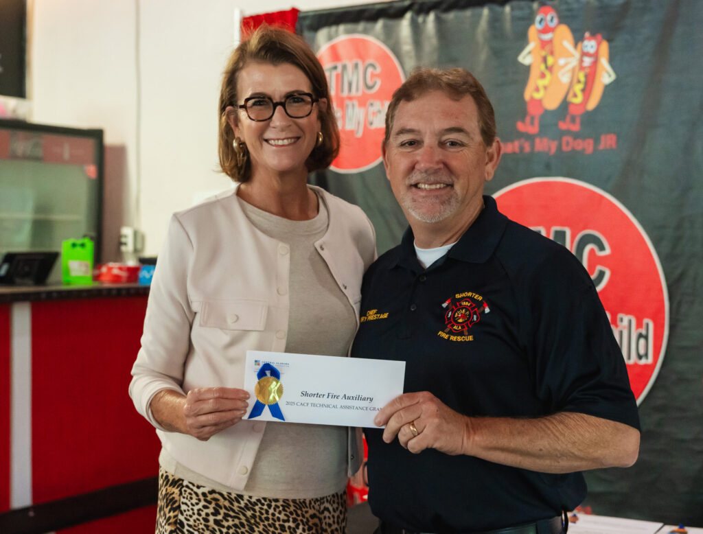 CACF representative Burton Crenshaw holding a check with Shorter Fire Department Grant Recipient