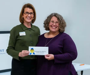 Burton Crenshaw posing with grant recipient holding envelope and smiling