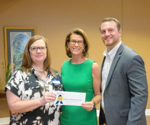 Burton Crenshaw in green smiling with two recipients of education grants from CACF