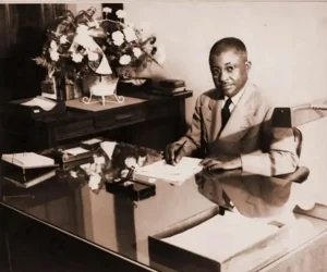 Dr. JF Drake seated at a desk